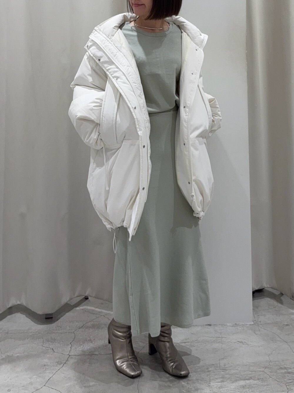 グリーン系のニット/セーター、グリーン系のスカート、シルバー系のブーツを着用したレディースの冬コーディネートの8枚目の写真