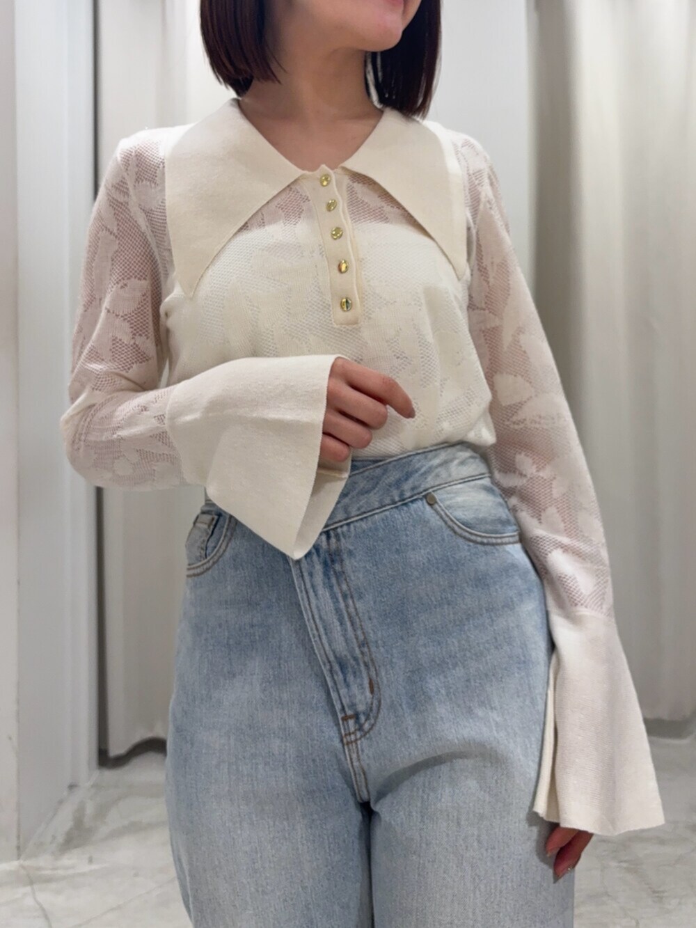 ブルー系のデニムパンツ、ブラウン系のハンドバッグ、ホワイト系のサンダルを着用したレディースの春コーディネートの5枚目の写真