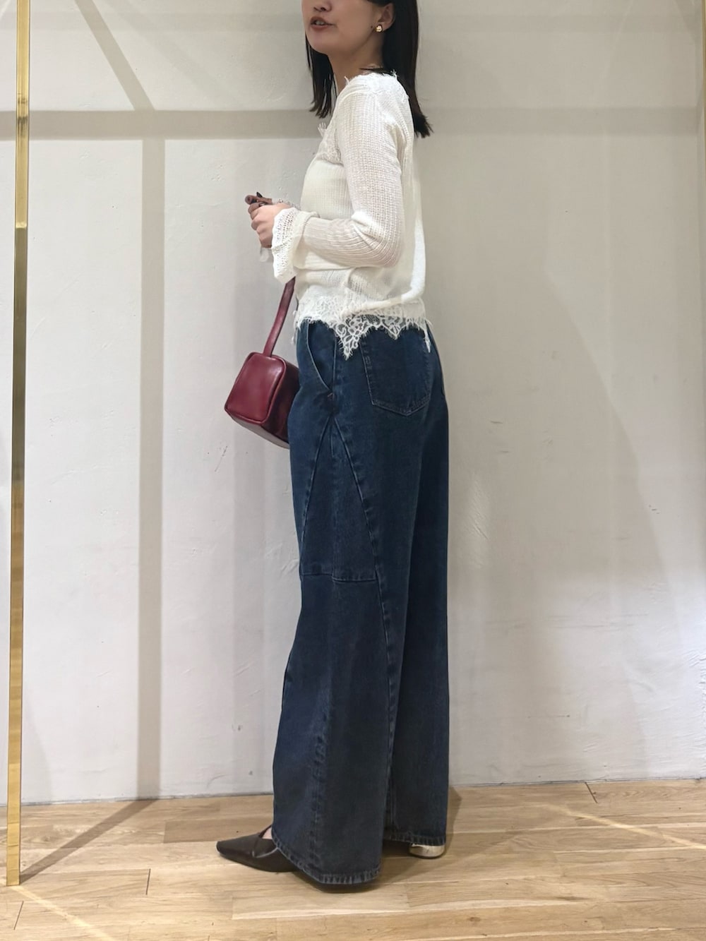 ホワイト系のカーディガン/ボレロ、ブルー系のデニムパンツ、レッド系のハンドバッグを着用したレディースの秋コーディネートの3枚目の写真