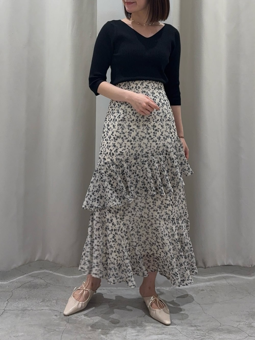 ブラック系のニット/セーター、ホワイト系のスカート、ホワイト系のサンダルを着用したレディースの春コーディネートの3枚目の写真