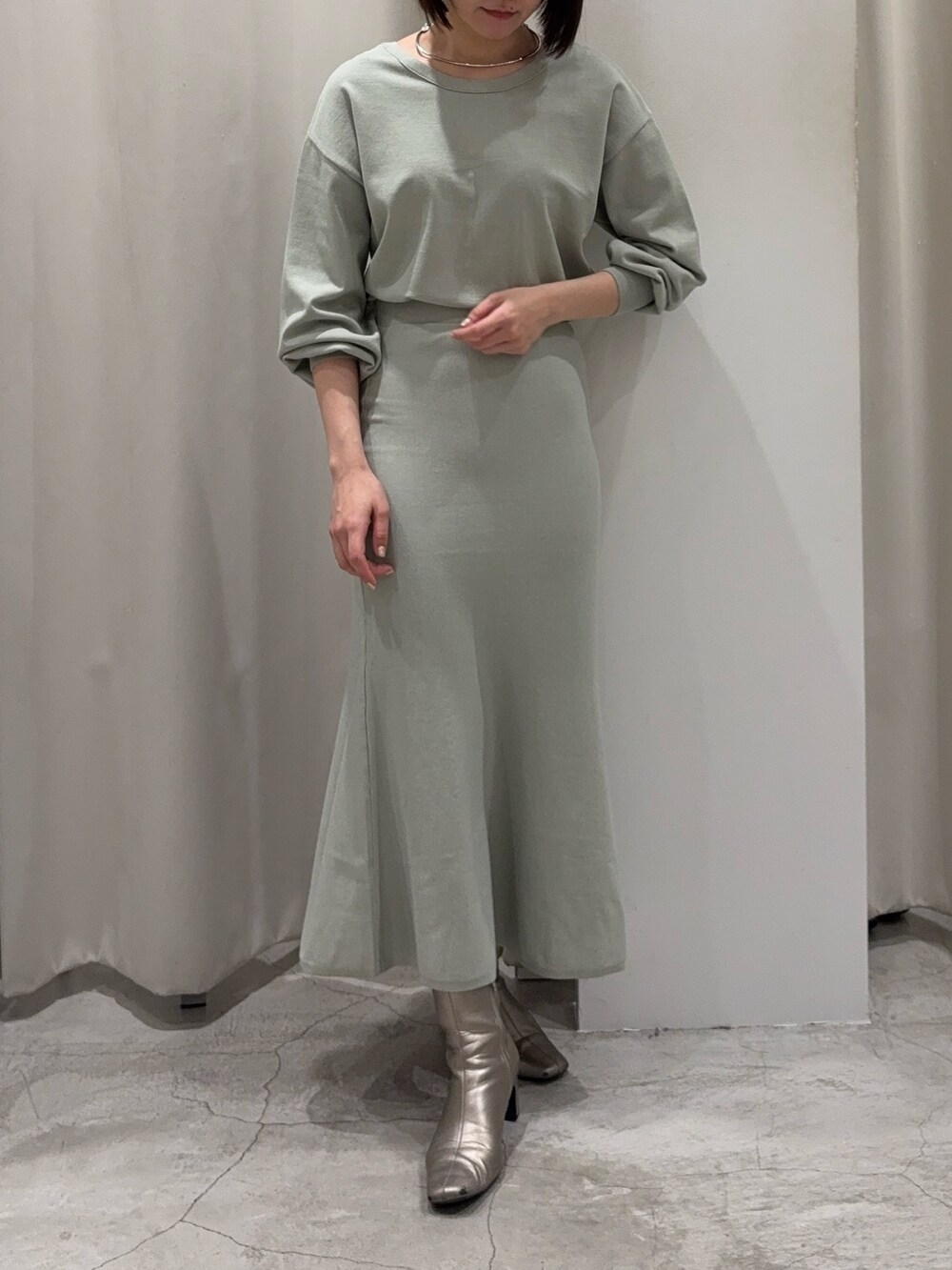 グリーン系のニット/セーター、グリーン系のスカート、シルバー系のブーツを着用したレディースの冬コーディネートの4枚目の写真