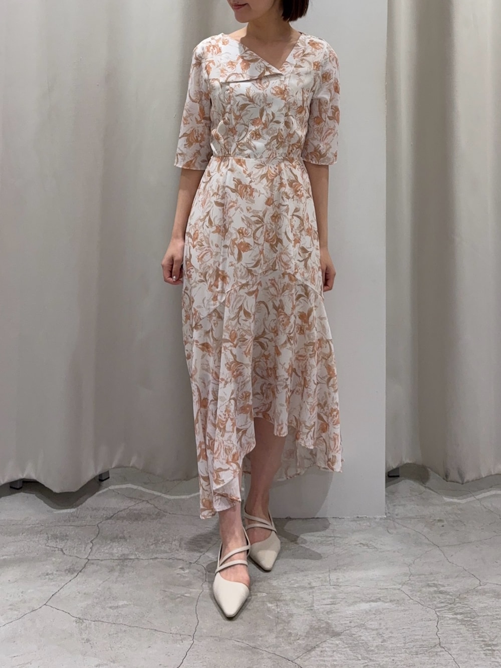 オレンジ系のワンピース、ホワイト系のパンプス、ホワイト系のカーディガン/ボレロを着用したレディースの冬コーディネートの2枚目の写真