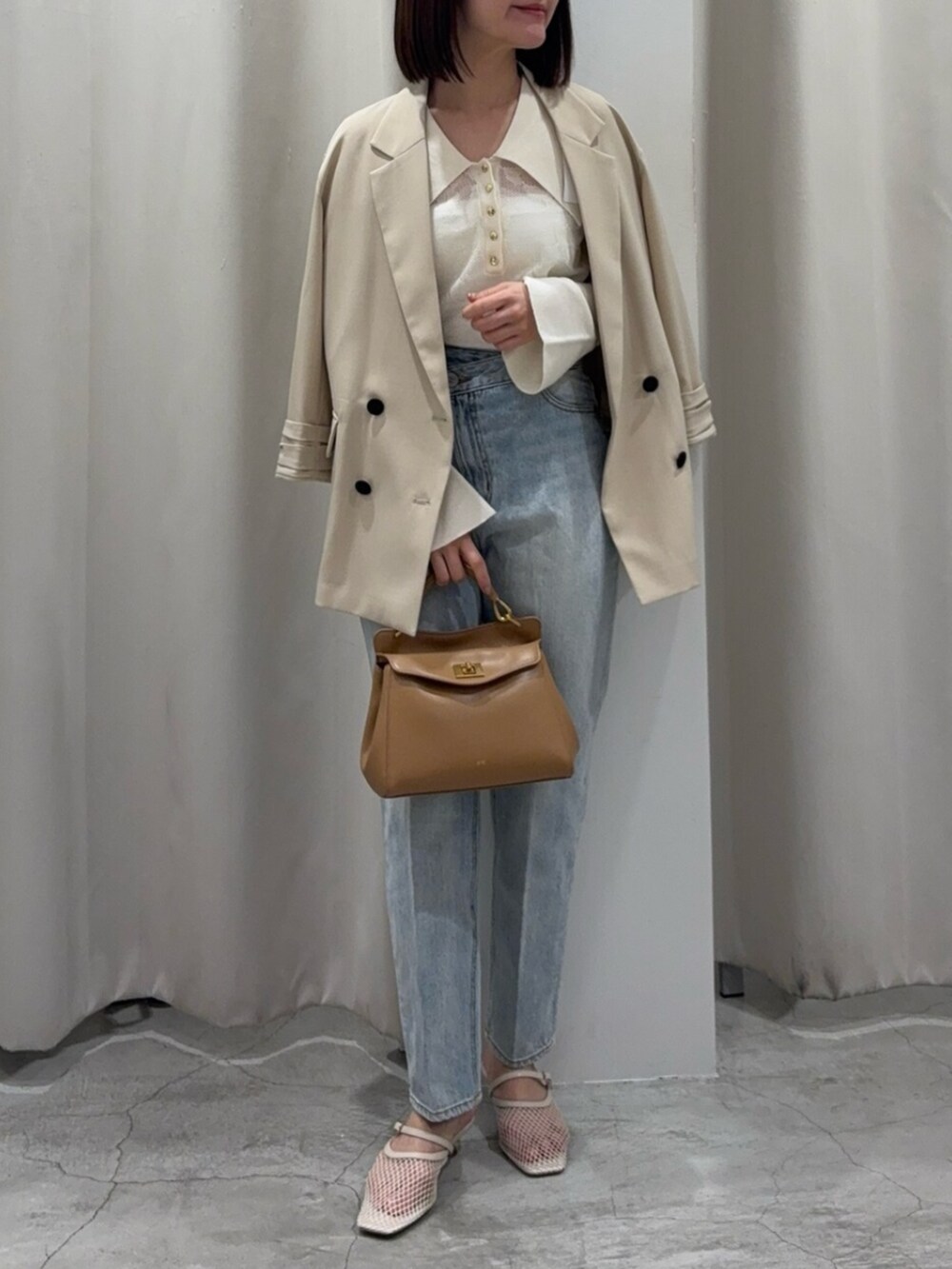 ブルー系のデニムパンツ、ブラウン系のハンドバッグ、ホワイト系のサンダルを着用したレディースの春コーディネートの8枚目の写真