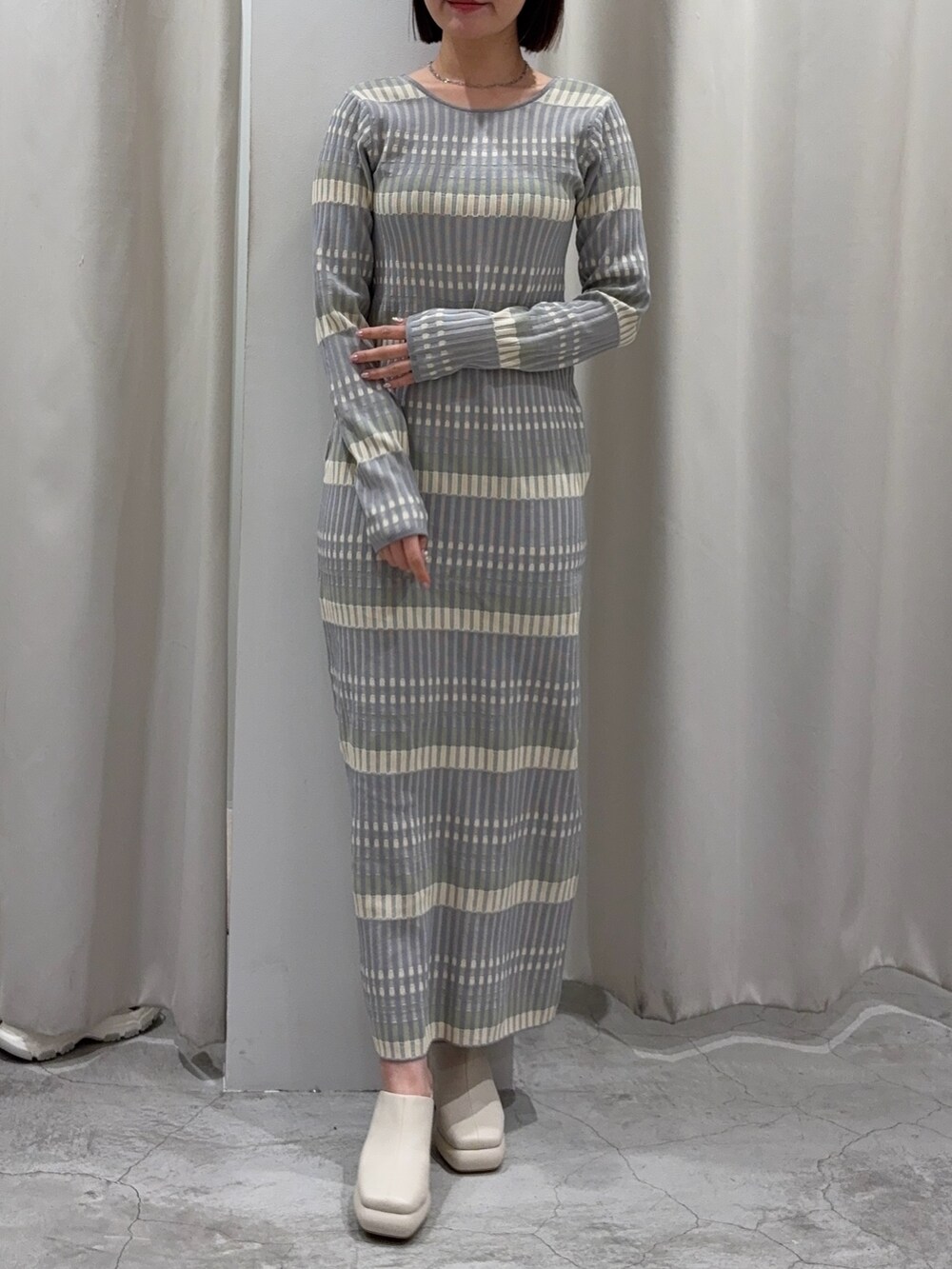 グレー系のワンピース、ホワイト系のカーディガン/ボレロ、ホワイト系のサンダルを着用したレディースの冬コーディネートの2枚目の写真