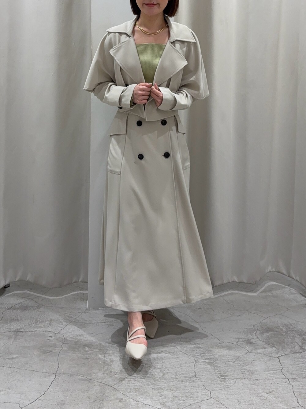 ホワイト系のトレンチコート、グリーン系のニット/セーター、ホワイト系のパンプスを着用したレディースの冬コーディネートの5枚目の写真