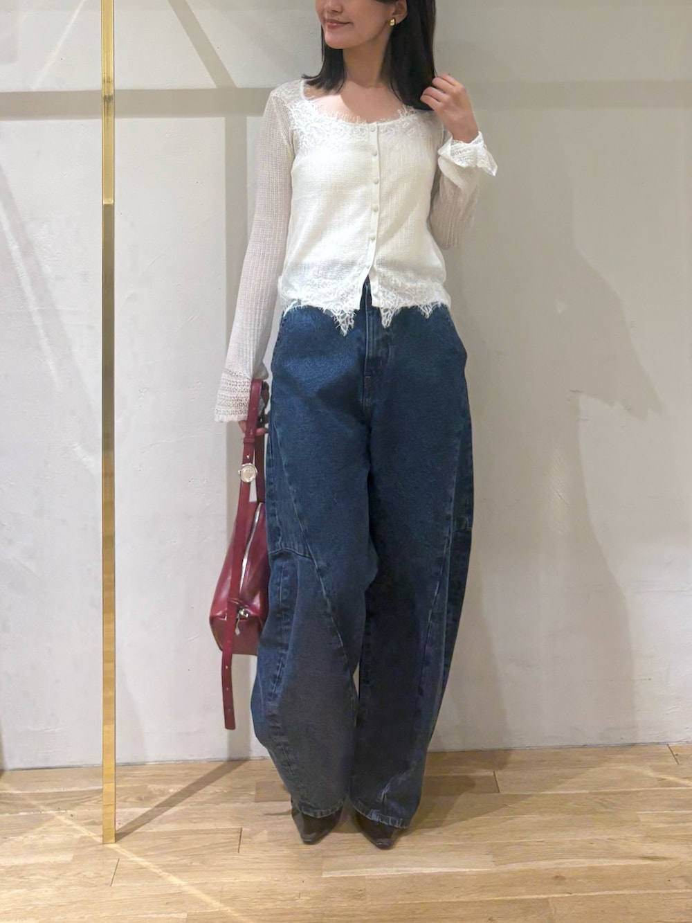 ホワイト系のカーディガン/ボレロ、ブルー系のデニムパンツ、レッド系のハンドバッグを着用したレディースの秋コーディネートの6枚目の写真