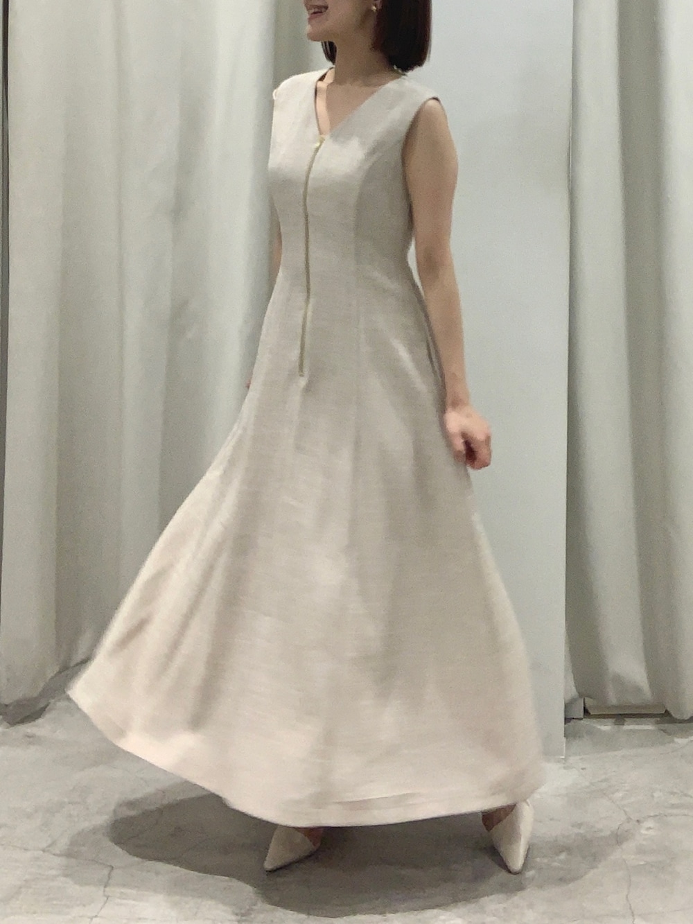 ベージュ系のワンピース、ホワイト系のショルダーバッグ、ホワイト系のパンプスを着用したレディースの夏コーディネートの5枚目の写真