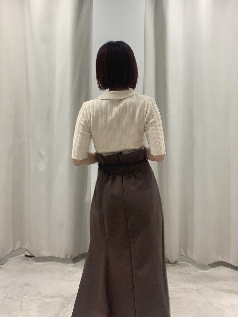 ブラウン系のスカート、ホワイト系のニット/セーター、ホワイト系のショルダーバッグを着用したレディースの夏コーディネートの4枚目の写真