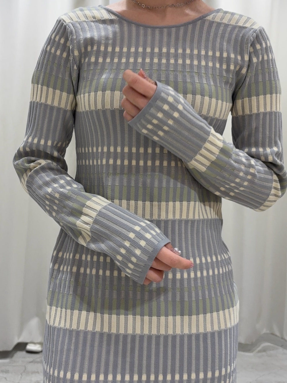 グレー系のワンピース、ホワイト系のカーディガン/ボレロ、ホワイト系のサンダルを着用したレディースの冬コーディネートの4枚目の写真