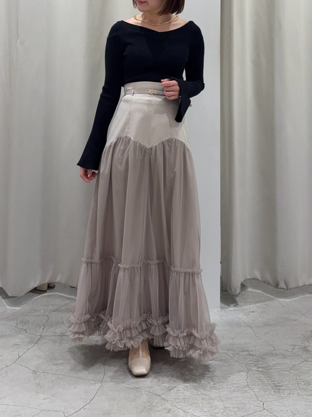 ベージュ系のスカート、ブラック系のニット/セーターを着用したレディースの春コーディネートの4枚目の写真