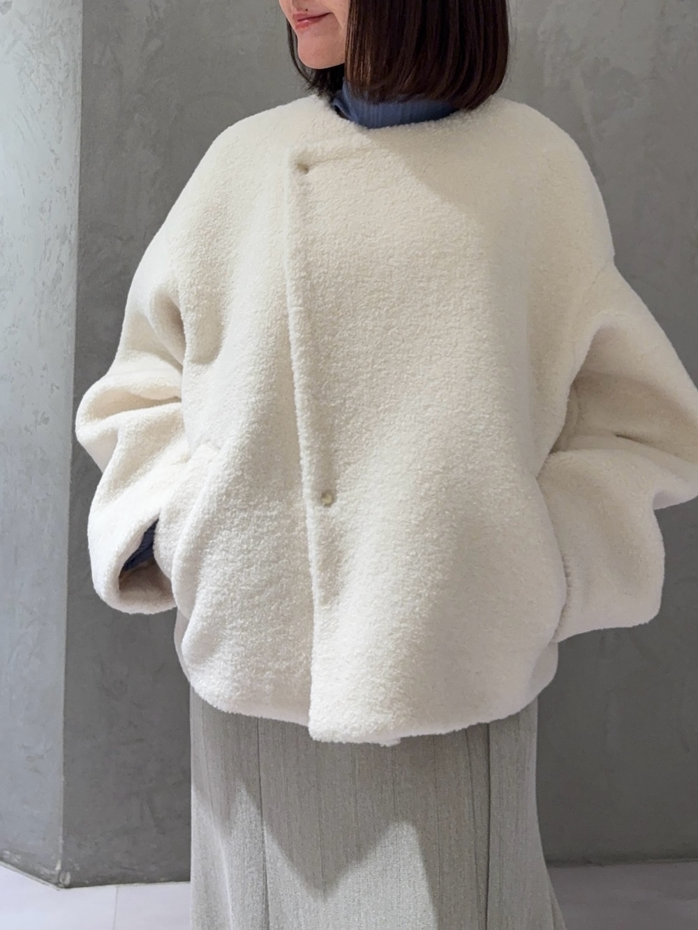 ホワイト系のブルゾン、グレー系のスカート、ブルー系のニット/セーターを着用したレディースの冬コーディネートの4枚目の写真