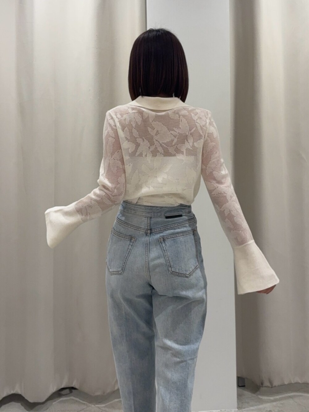 ブルー系のデニムパンツ、ブラウン系のハンドバッグ、ホワイト系のサンダルを着用したレディースの春コーディネートの6枚目の写真