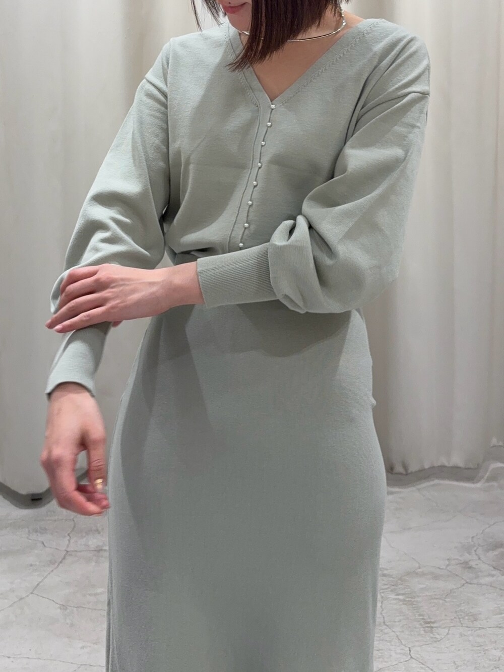 グリーン系のニット/セーター、グリーン系のスカート、シルバー系のブーツを着用したレディースの冬コーディネートの2枚目の写真