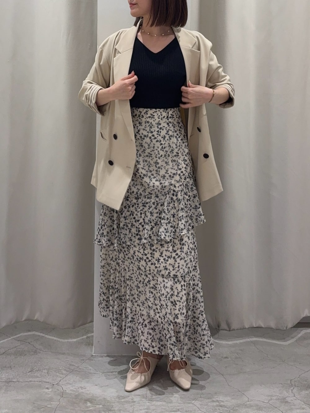 ブラック系のニット/セーター、ホワイト系のスカート、ホワイト系のサンダルを着用したレディースの春コーディネートの2枚目の写真