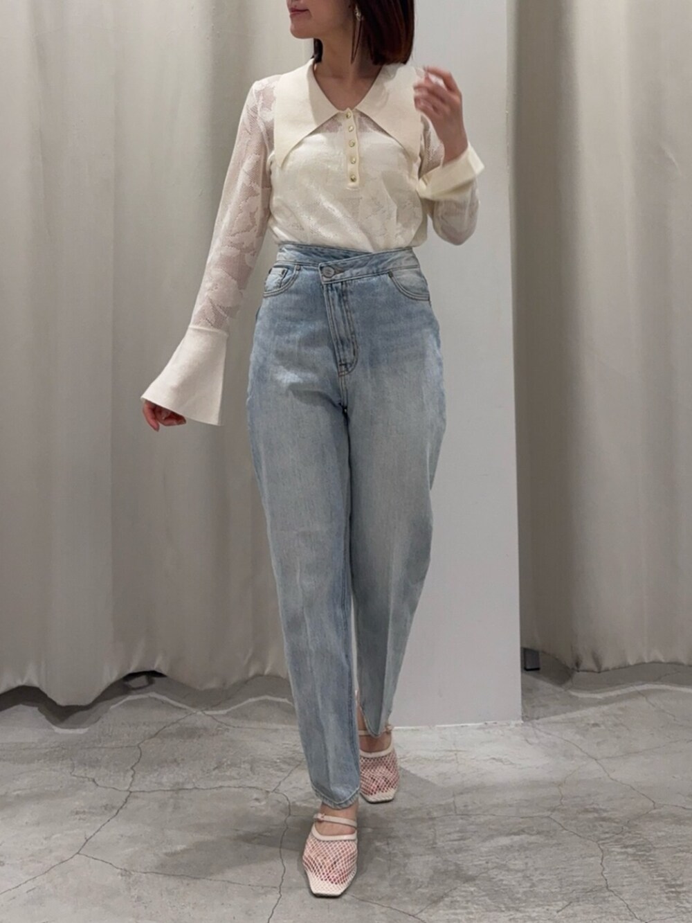 ブルー系のデニムパンツ、ブラウン系のハンドバッグ、ホワイト系のサンダルを着用したレディースの春コーディネートの4枚目の写真