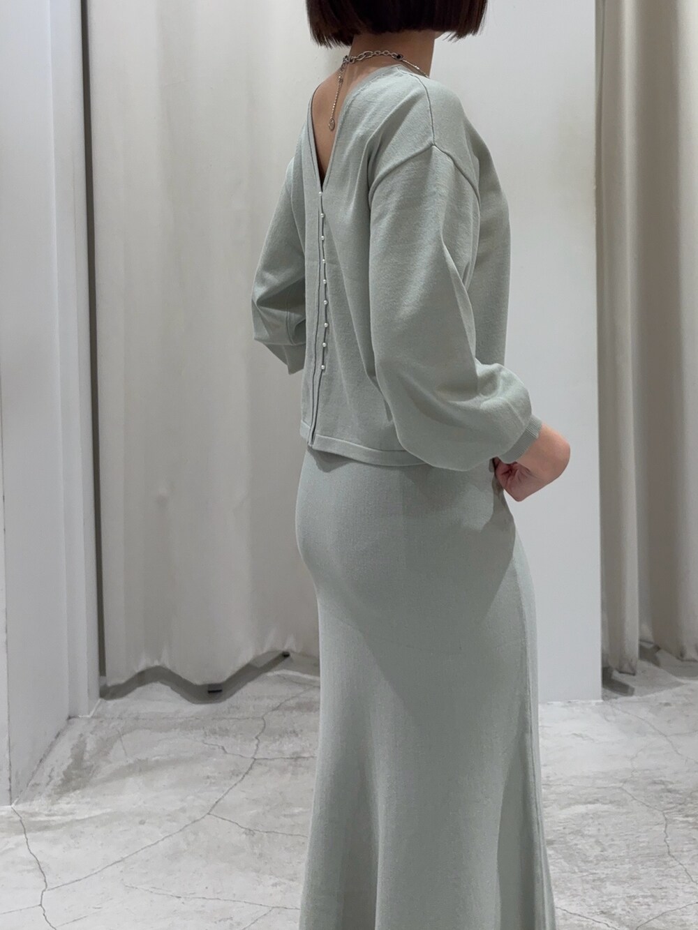 グリーン系のニット/セーター、グリーン系のスカート、シルバー系のブーツを着用したレディースの冬コーディネートの7枚目の写真