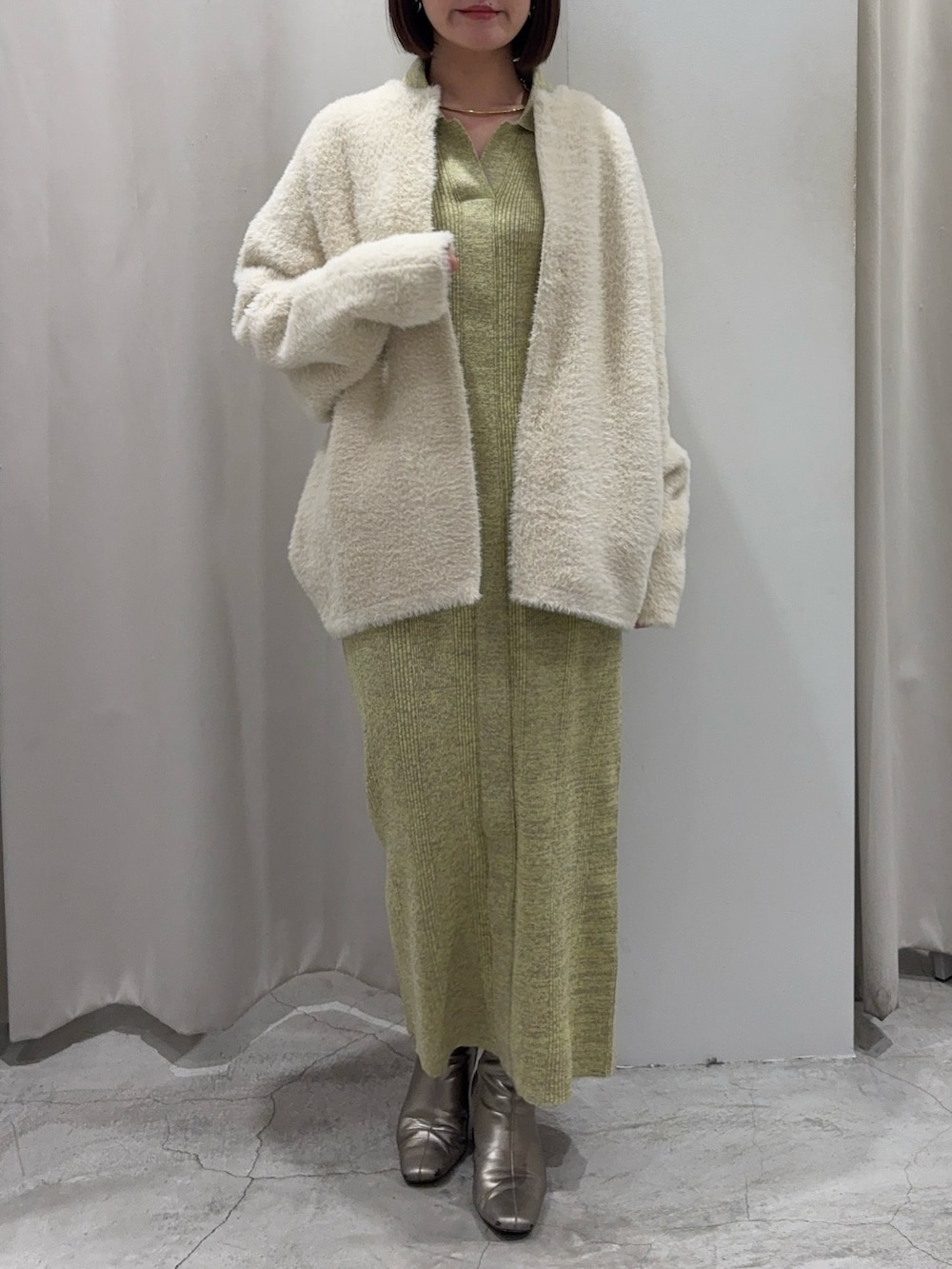 ホワイト系のカーディガン/ボレロ、グリーン系のワンピース、ホワイト系のショルダーバッグを着用したレディースの冬コーディネートの2枚目の写真
