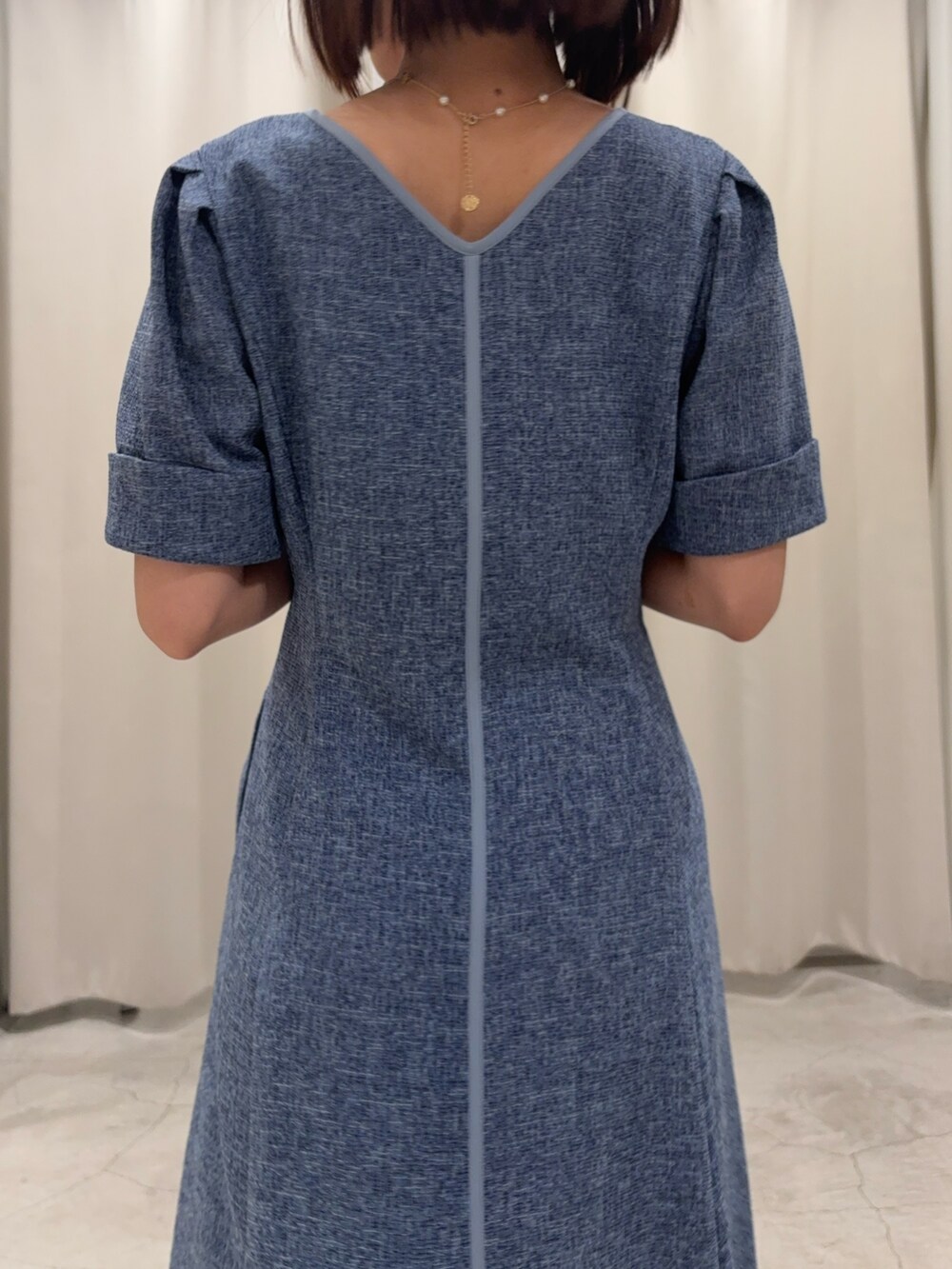 ブルー系のワンピース、ホワイト系のサンダル、ゴールド系のネックレスを着用したレディースの春コーディネートの5枚目の写真