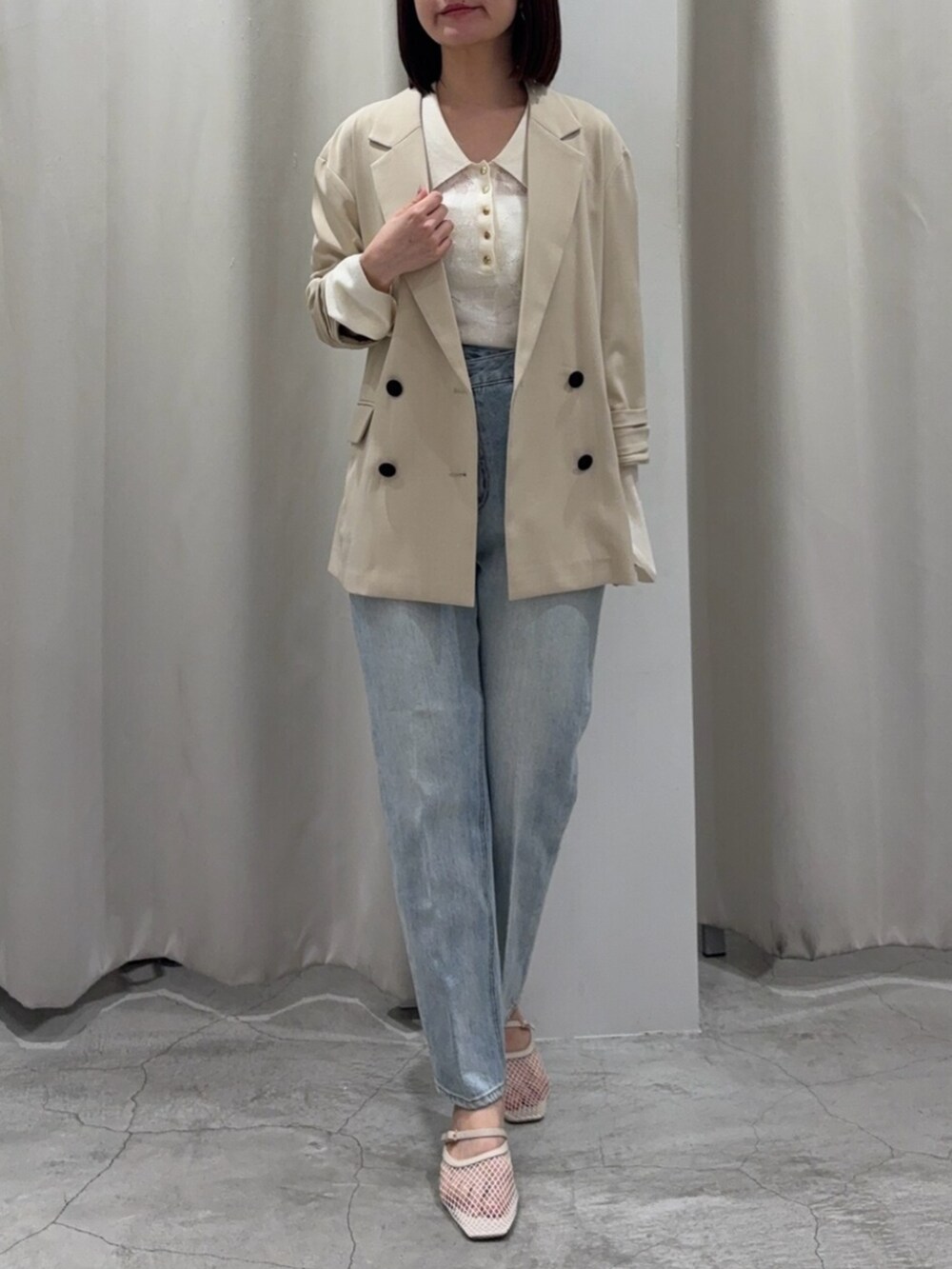 ブルー系のデニムパンツ、ブラウン系のハンドバッグ、ホワイト系のサンダルを着用したレディースの春コーディネートの3枚目の写真