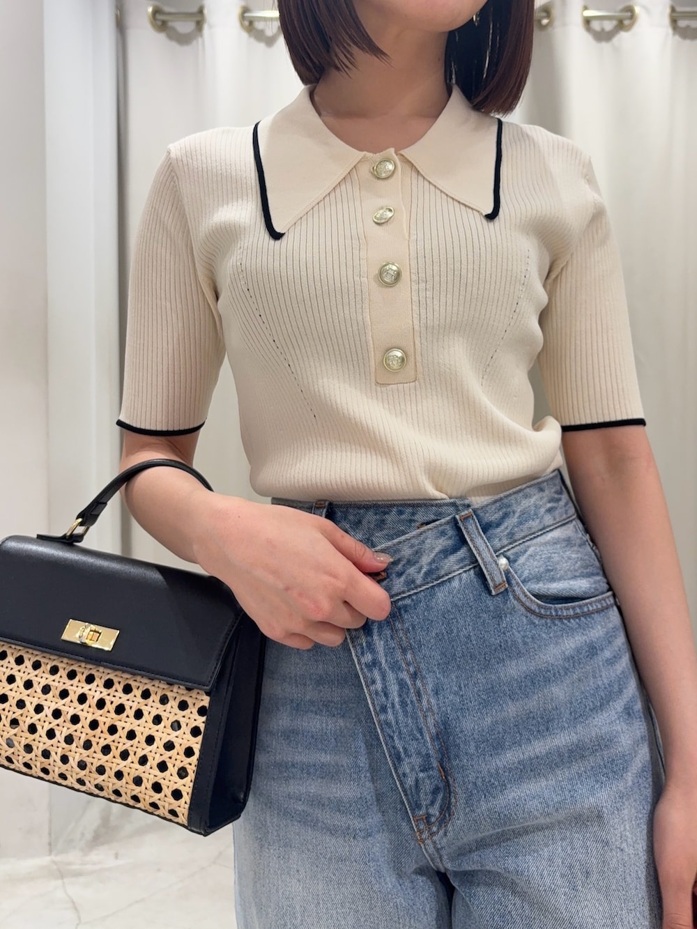 ブルー系のデニムパンツ、ブラック系のハンドバッグ、ホワイト系のニット/セーターを着用したレディースの春コーディネートの3枚目の写真