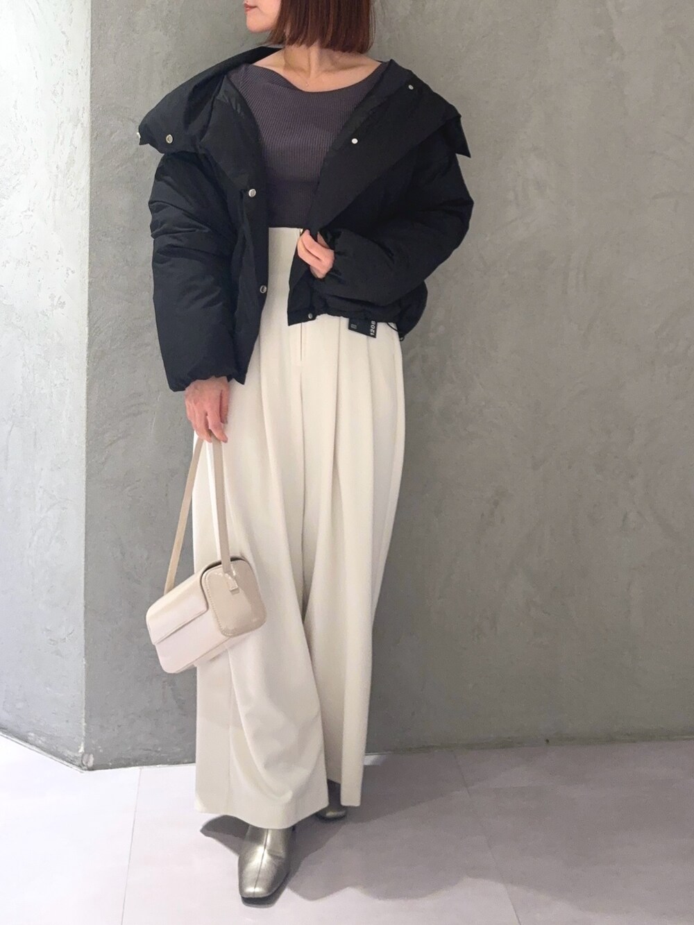 グレー系のニット/セーター、ホワイト系のその他パンツ、ブラック系のダウンジャケット/コートを着用したレディースの秋コーディネートの4枚目の写真