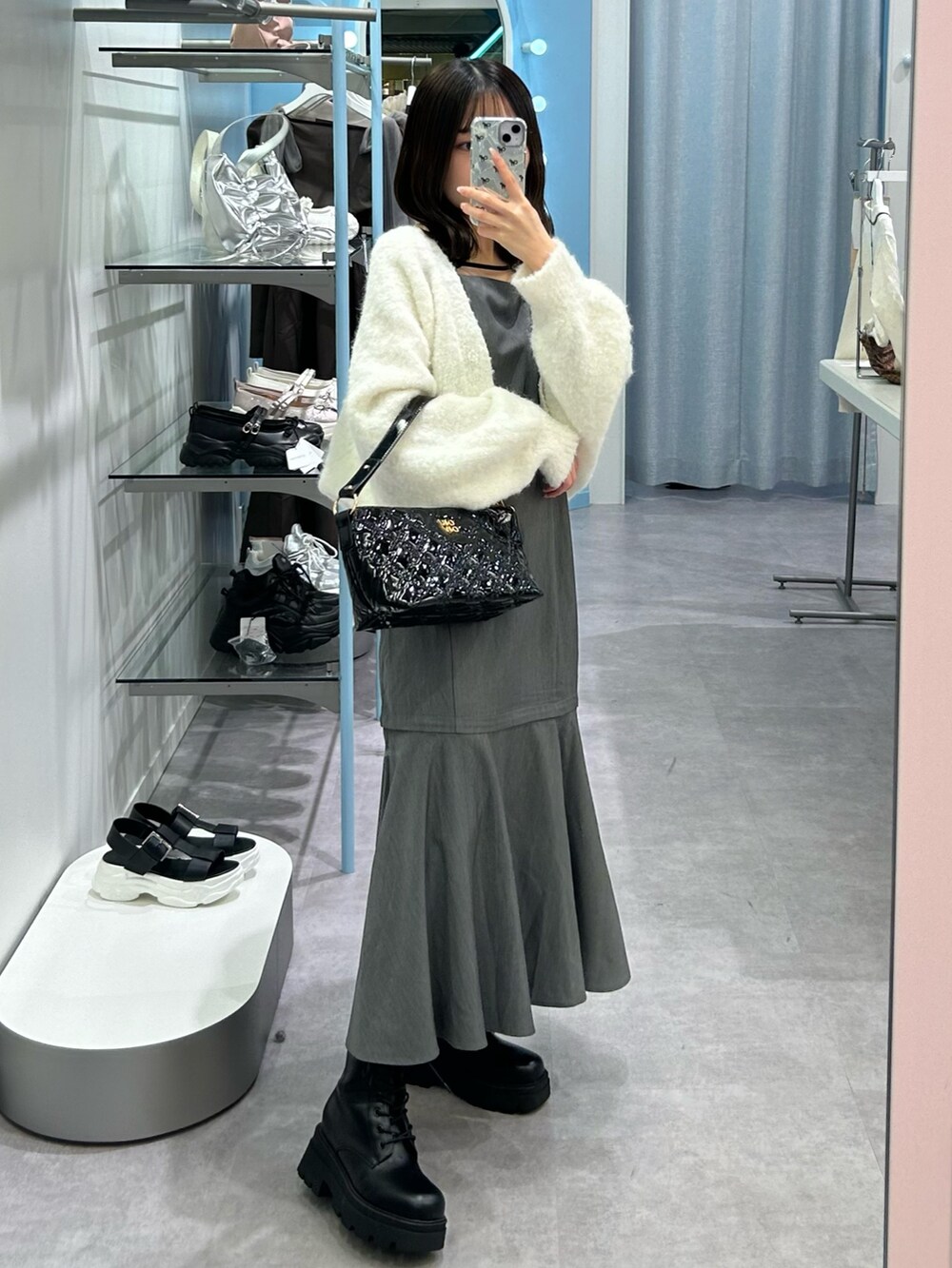 グレー系のワンピース、ホワイト系のカーディガン/ボレロ、ブラック系のショルダーバッグを着用したレディースの秋コーディネートの2枚目の写真