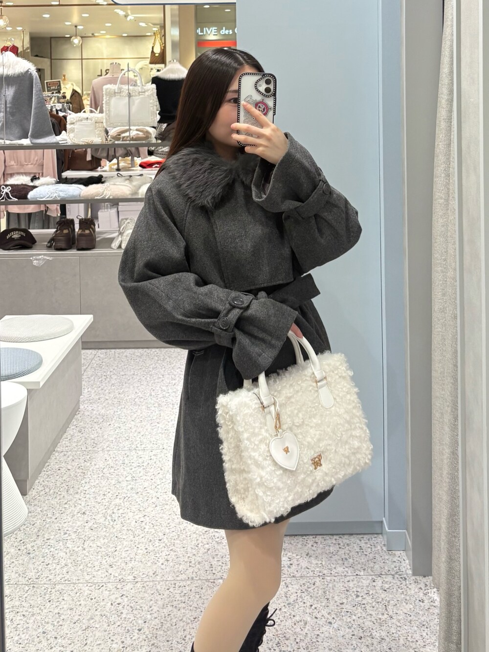 ホワイト系のトートバッグ、グレー系のステンカラーコート、ブラック系のブーツを着用したレディースの冬コーディネートの2枚目の写真