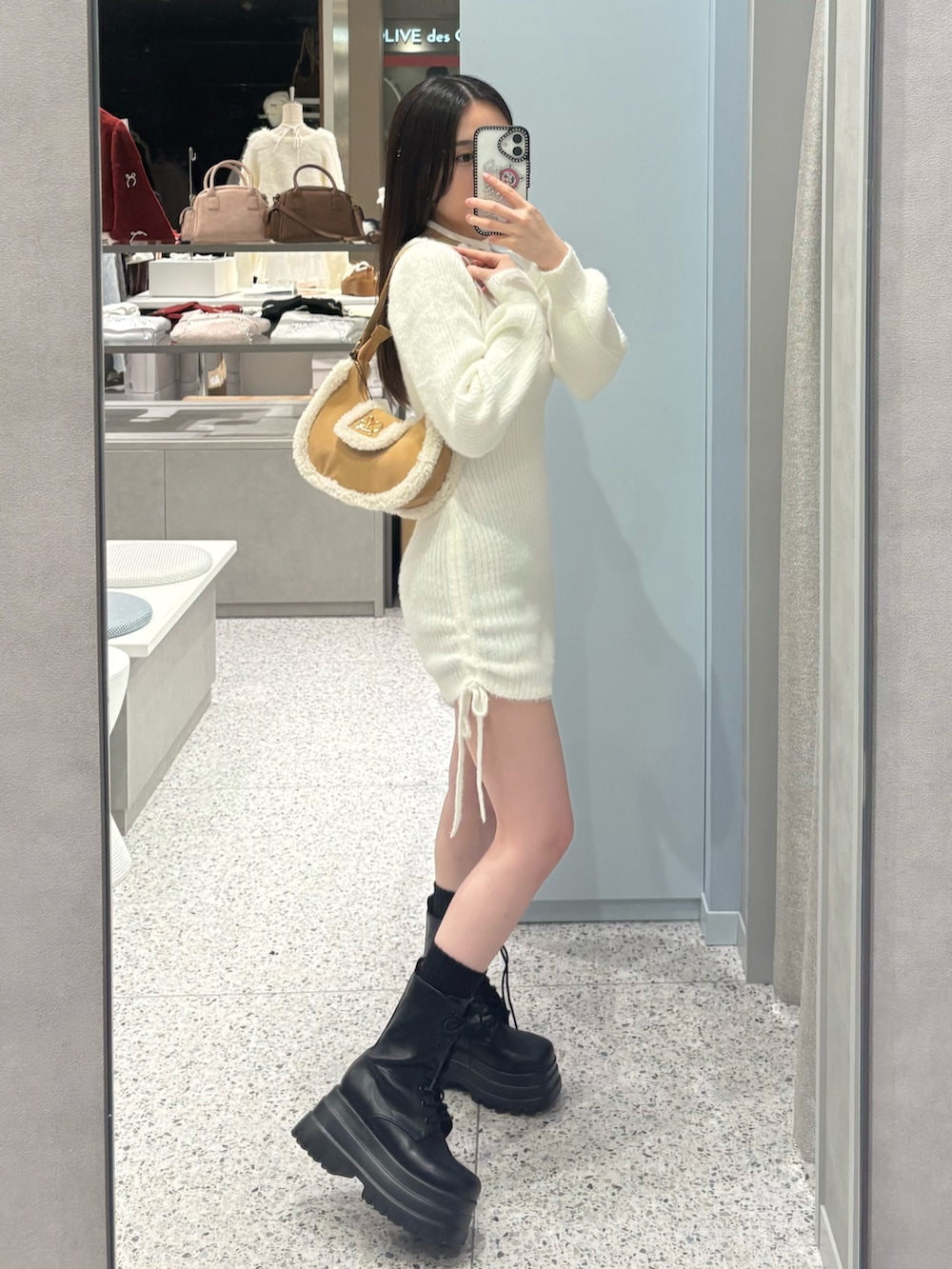 ホワイト系のワンピース、イエロー系のショルダーバッグ、ブラック系のブーツを着用したレディースの冬コーディネートの3枚目の写真