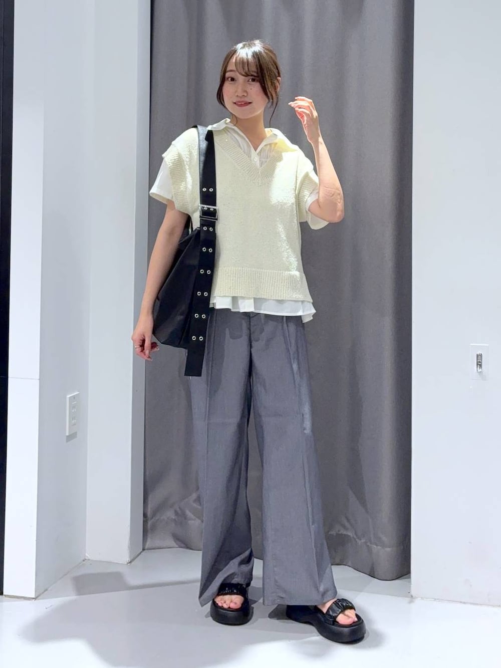 グレー系のスラックス、ブラック系のサンダル、ブラック系のショルダーバッグを着用したレディースの夏コーディネートの2枚目の写真