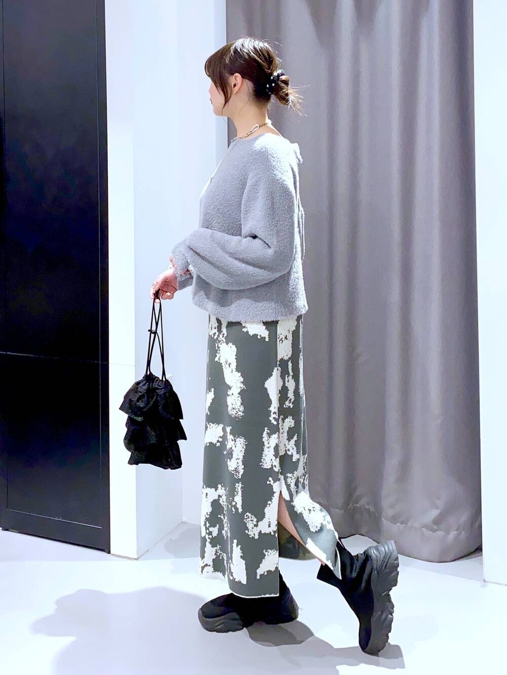 グレー系のスカート、ブラック系のブーツ、ブラック系のショルダーバッグを着用したレディースの秋コーディネートの3枚目の写真