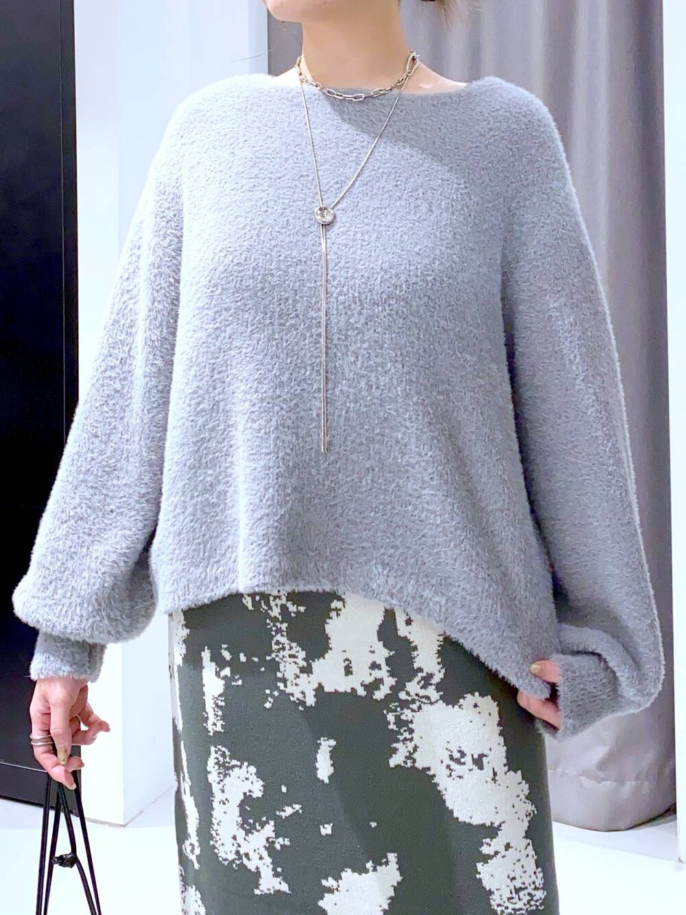 グレー系のスカート、ブラック系のブーツ、ブラック系のショルダーバッグを着用したレディースの秋コーディネートの6枚目の写真