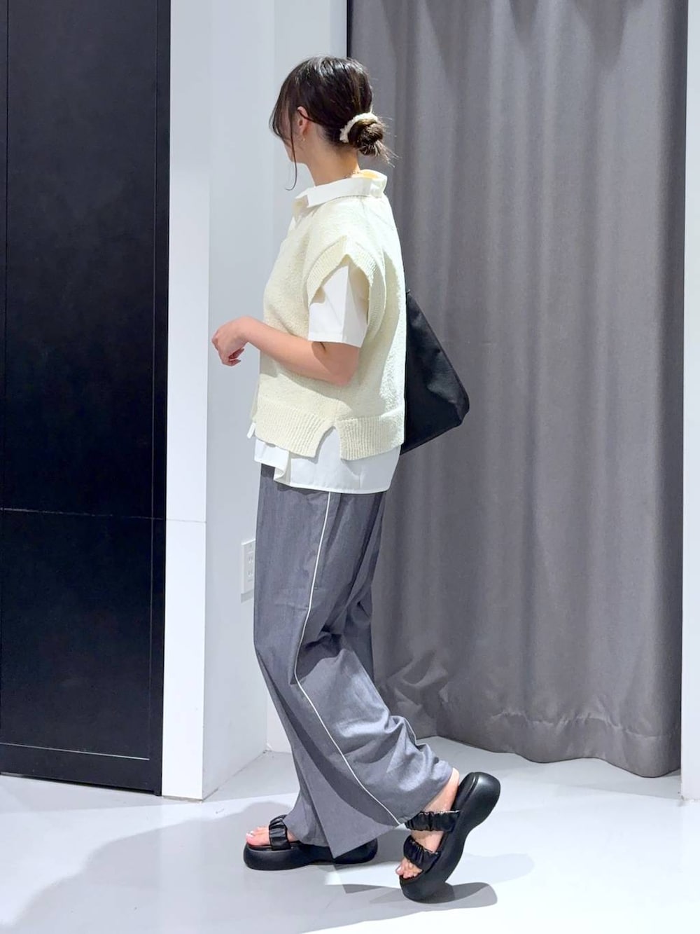 グレー系のスラックス、ブラック系のサンダル、ブラック系のショルダーバッグを着用したレディースの夏コーディネートの3枚目の写真