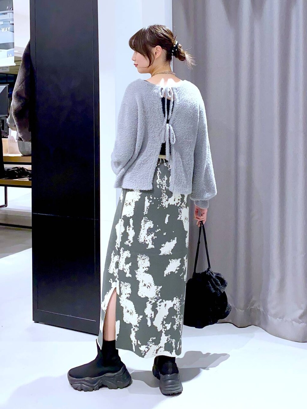 グレー系のスカート、ブラック系のブーツ、ブラック系のショルダーバッグを着用したレディースの秋コーディネートの4枚目の写真