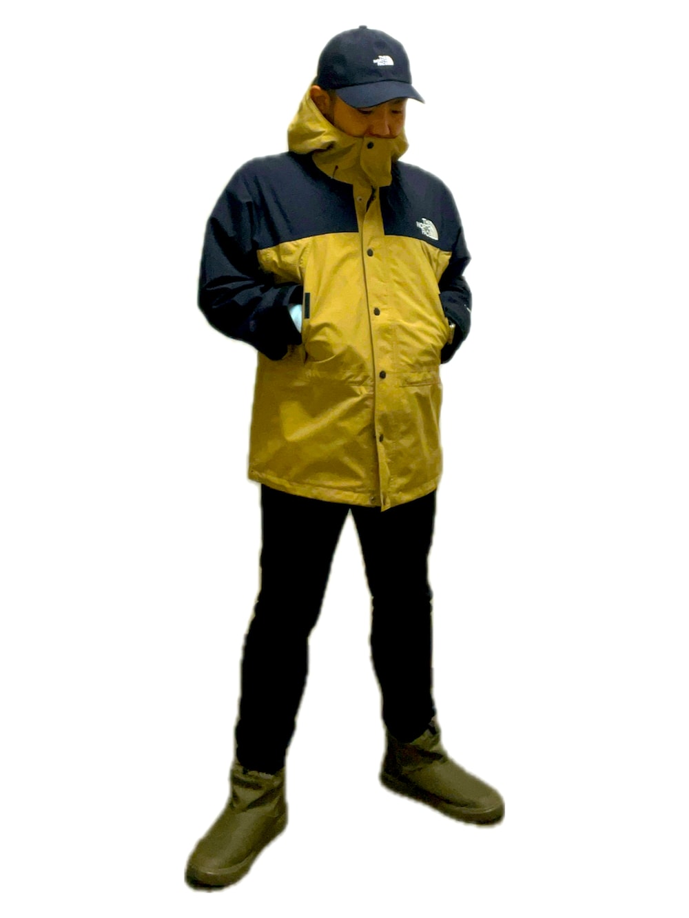 ベージュ系のマウンテンパーカー、グリーン系のレインシューズ、ブラック系のデニムパンツを着用したメンズの秋コーディネートの2枚目の写真