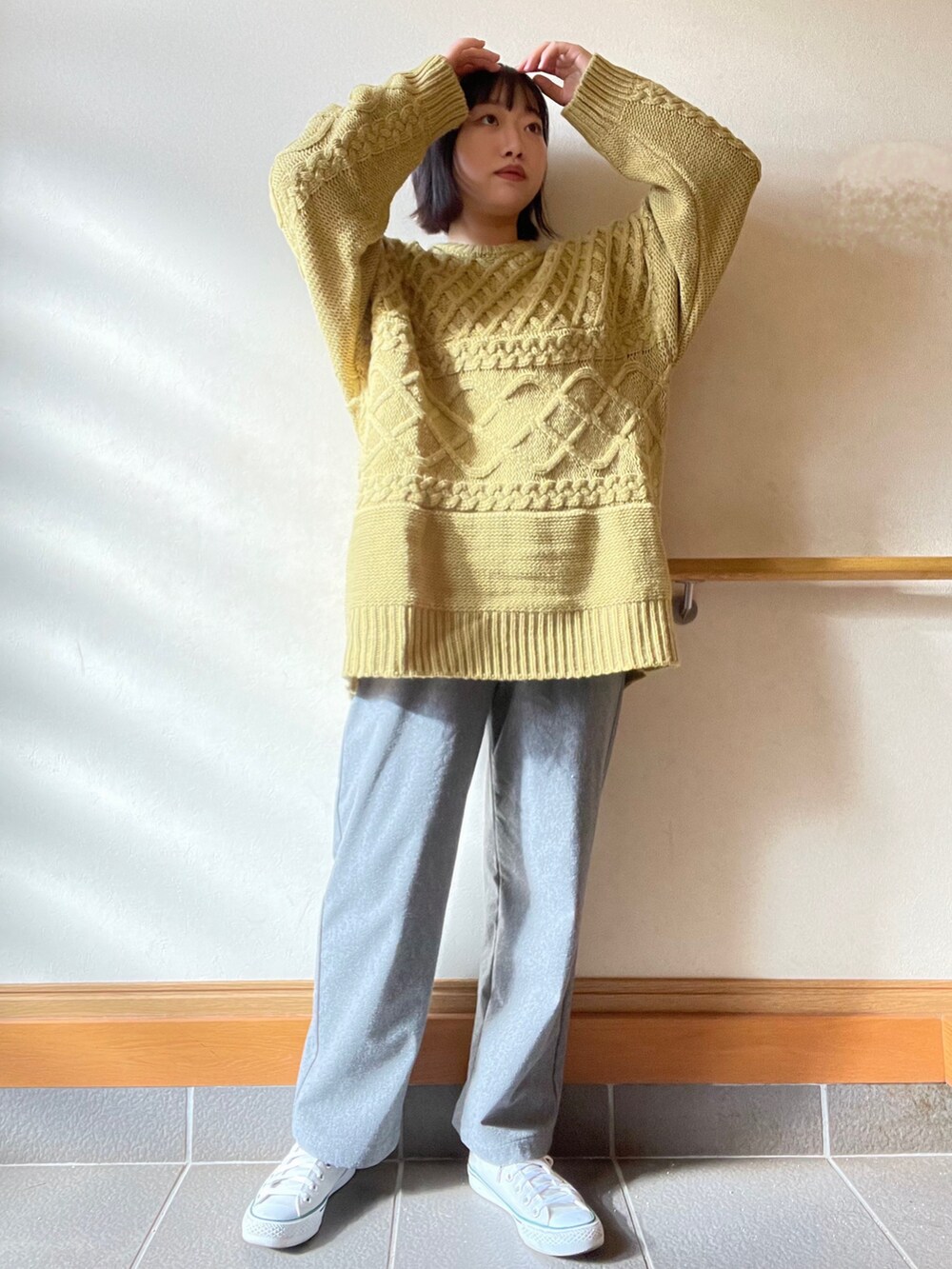 イエロー系のニット/セーター、グレー系のその他パンツ、グレー系のスニーカーを着用したレディースの冬コーディネートの2枚目の写真