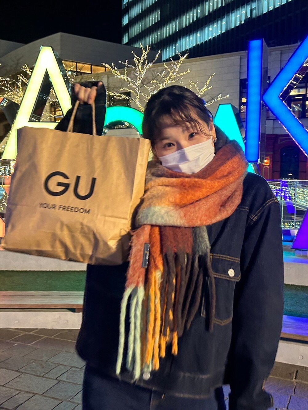 オレンジ系のバッグ、ブルー系のデニムジャケット、ブルー系のデニムパンツを着用したレディースの秋コーディネートの2枚目の写真