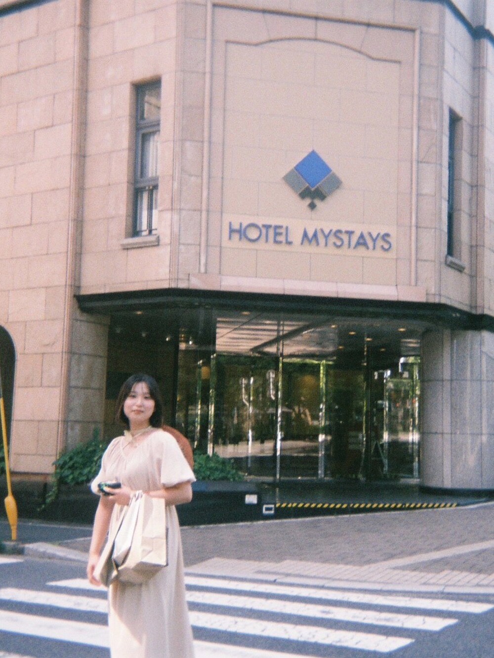 ベージュ系のワンピース、ベージュ系のハンドバッグ、オレンジ系のハットを着用したレディースの秋コーディネートの2枚目の写真