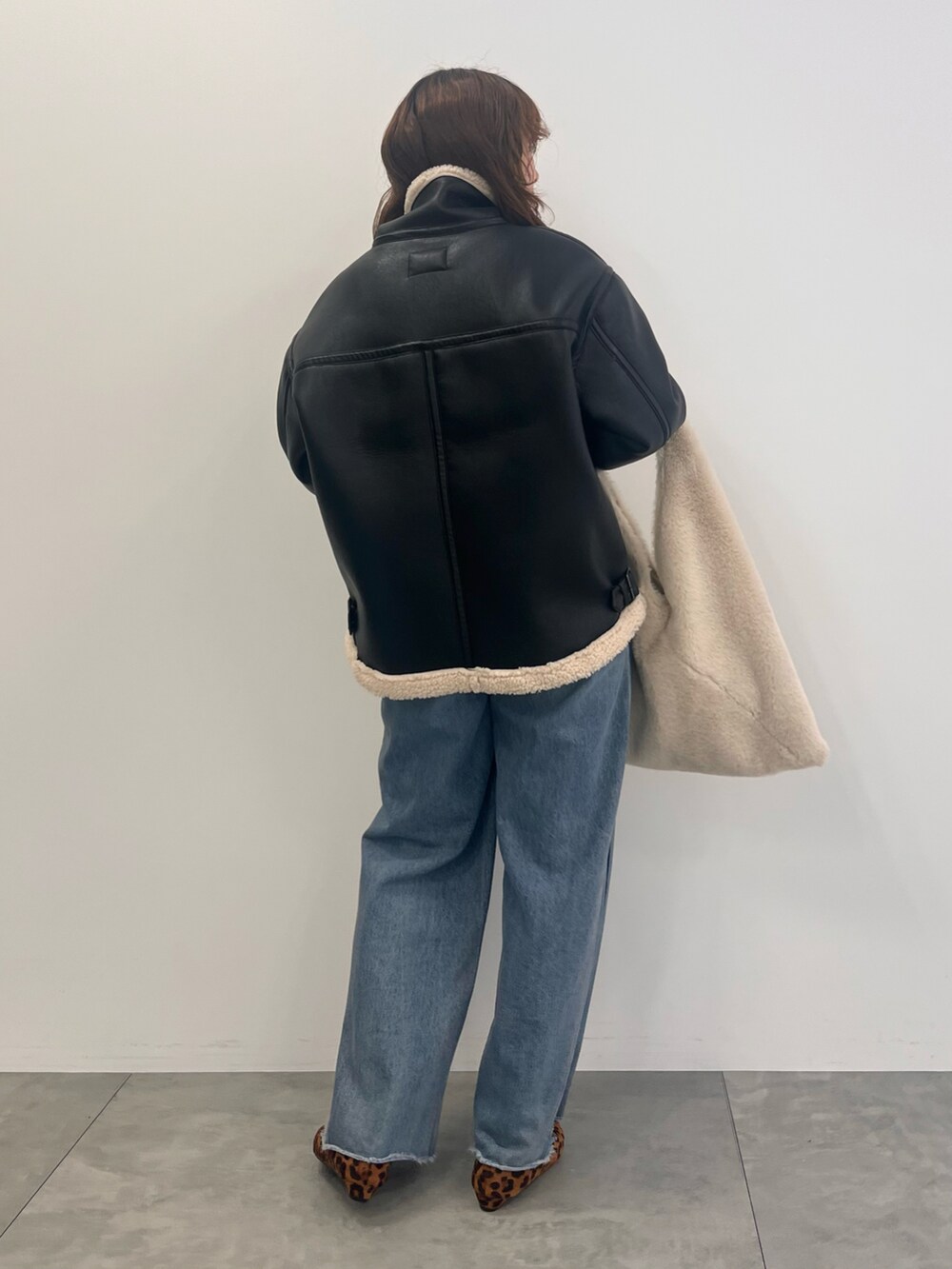 ブルー系のデニムパンツ、ブラック系のその他アウター、ベージュ系のショルダーバッグを着用したレディースの秋コーディネートの3枚目の写真