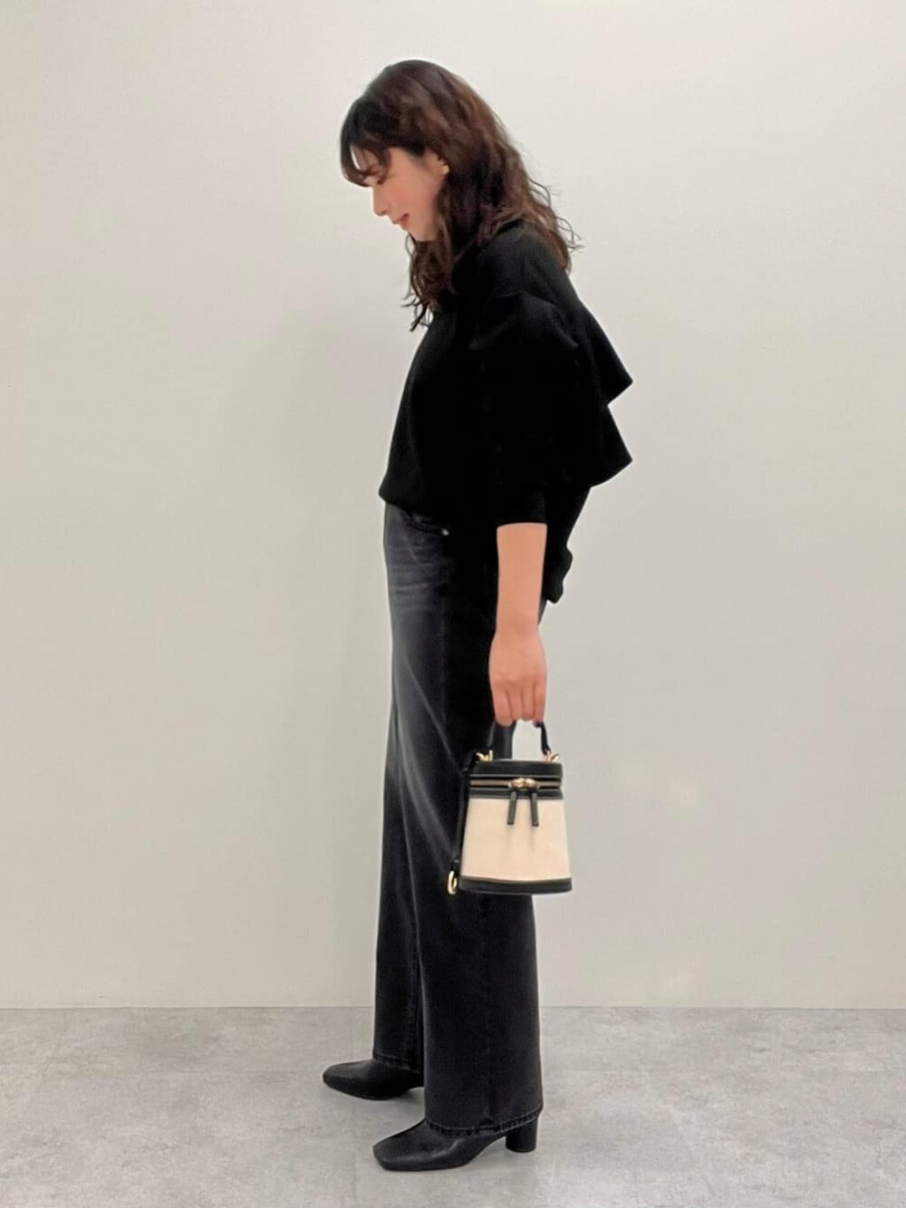 ブラック系のスウェット、ブラック系のデニムパンツを着用したレディースの冬コーディネートの3枚目の写真