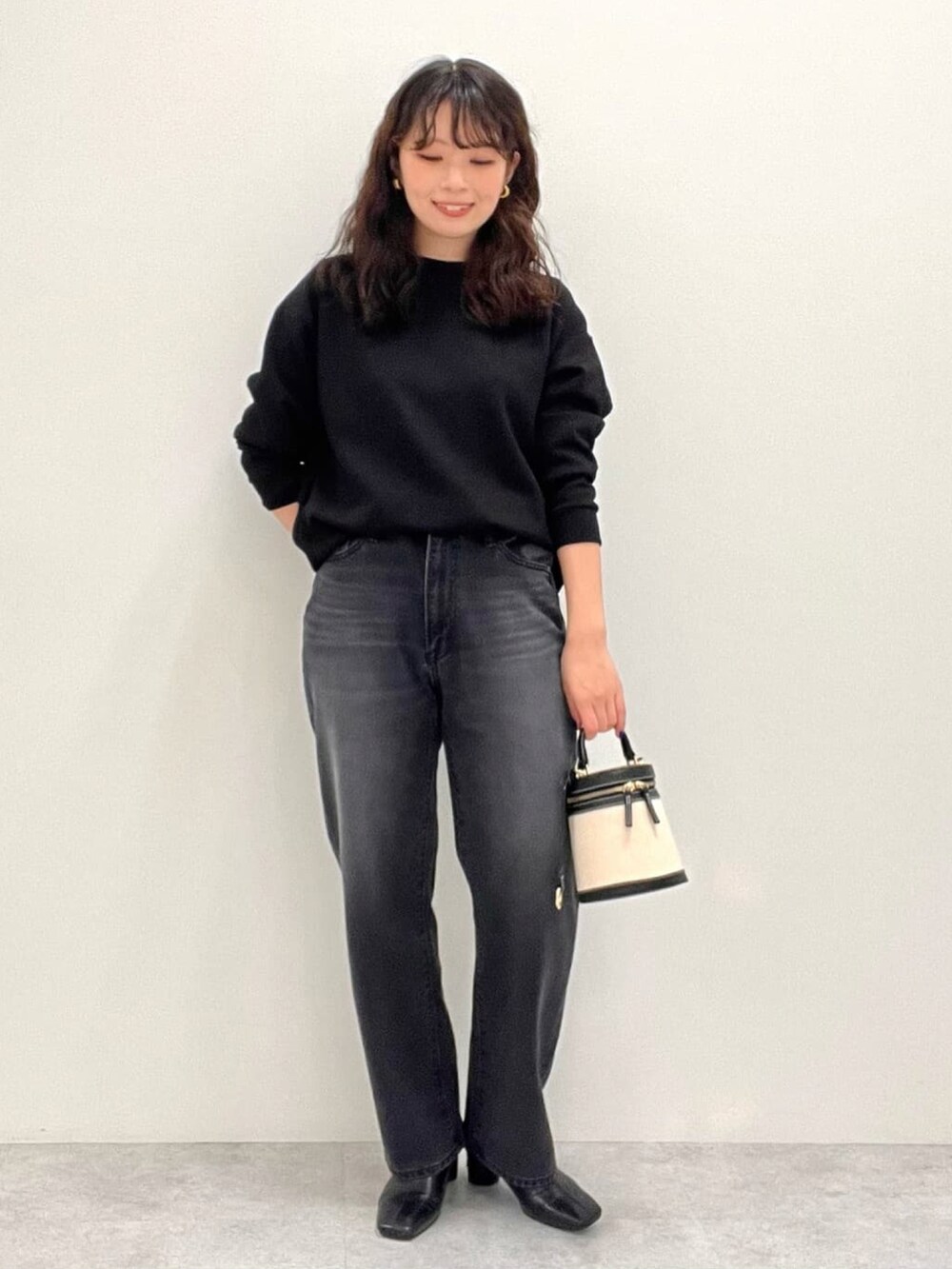 ブラック系のスウェット、ブラック系のデニムパンツを着用したレディースの冬コーディネートの2枚目の写真