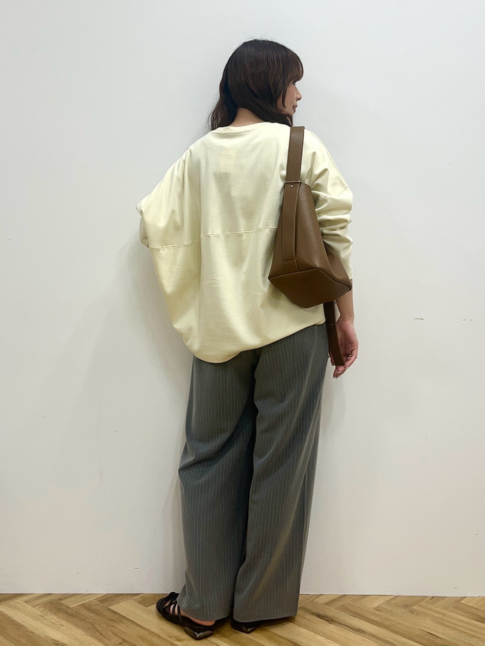 イエロー系のTシャツ/カットソー、グレー系のその他パンツ、ブラウン系のショルダーバッグを着用したレディースの冬コーディネートの3枚目の写真