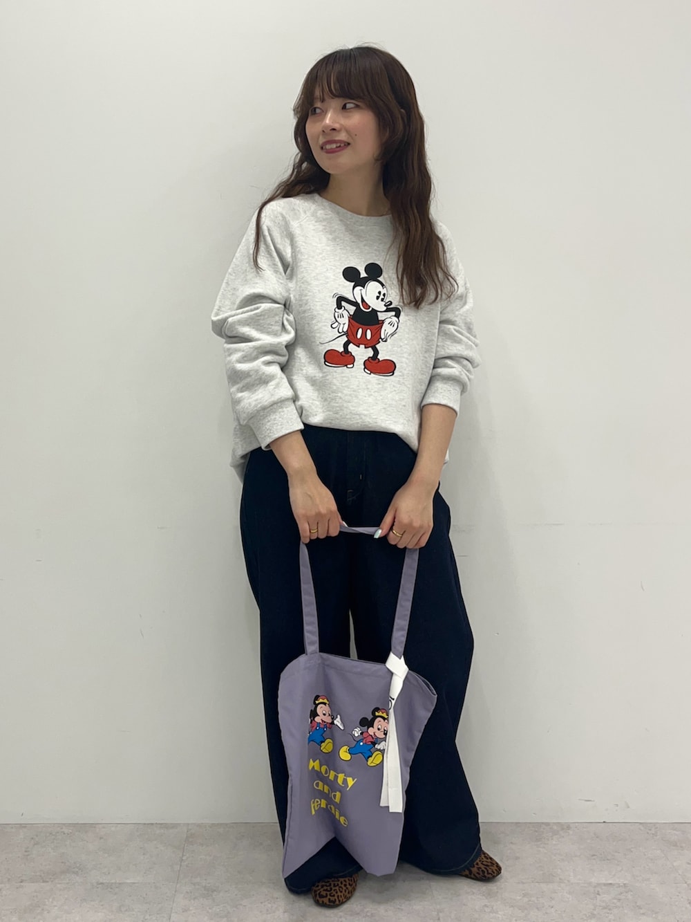 グレー系のスウェット、ブルー系のデニムパンツ、パープル系のトートバッグを着用したレディースの冬コーディネートの2枚目の写真