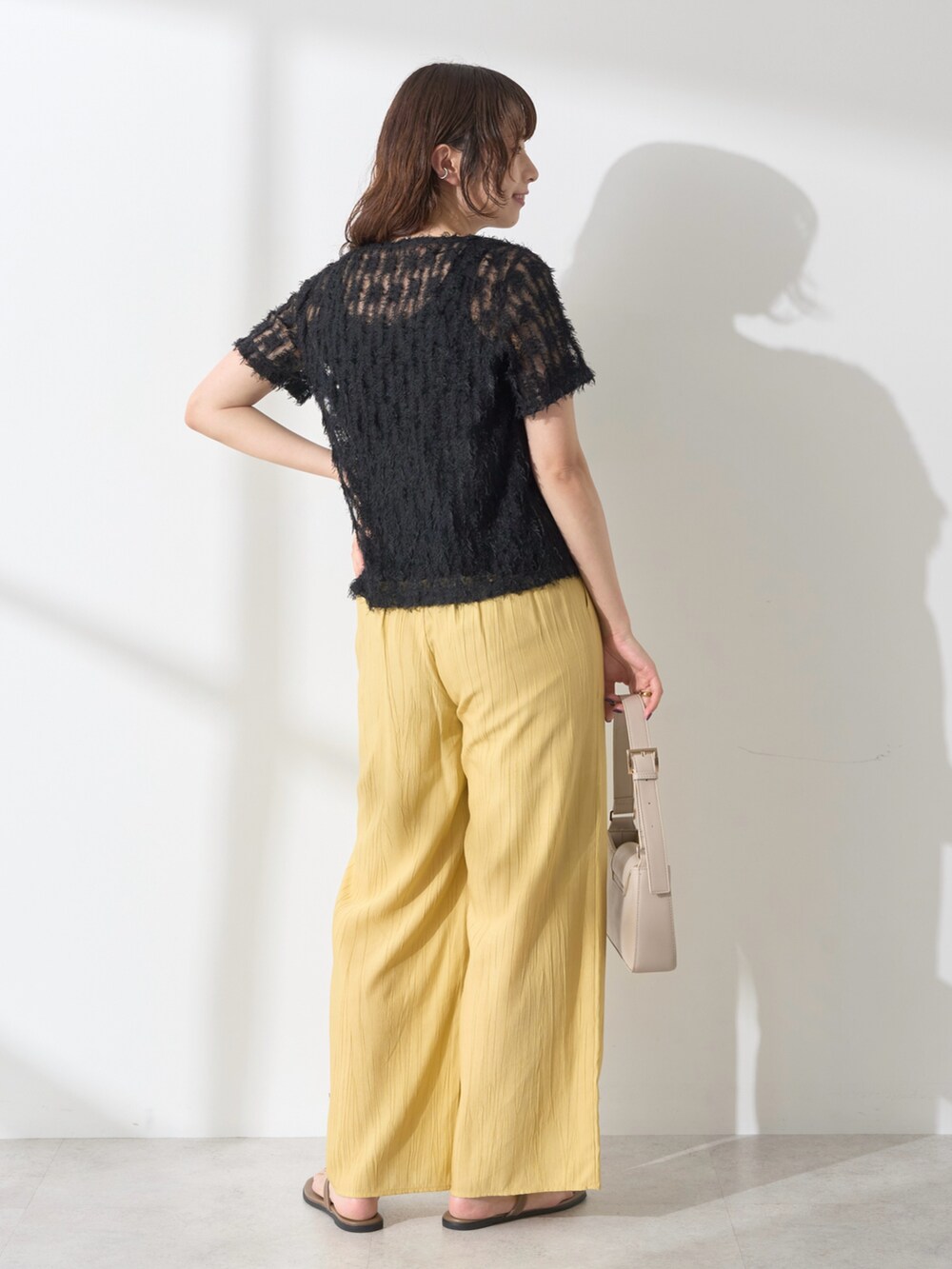 ブラック系のTシャツ/カットソー、イエロー系のその他パンツ、ベージュ系のショルダーバッグを着用したレディースの夏コーディネートの2枚目の写真