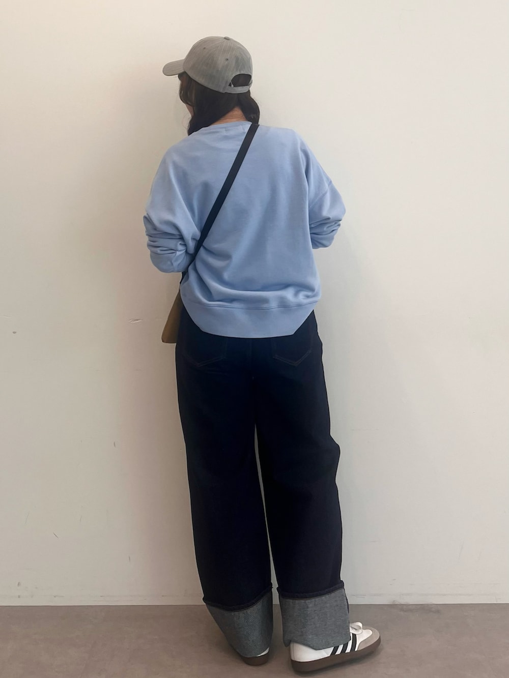 ブルー系のスウェット、ブルー系のデニムパンツ、ベージュ系のショルダーバッグを着用したレディースの冬コーディネートの3枚目の写真