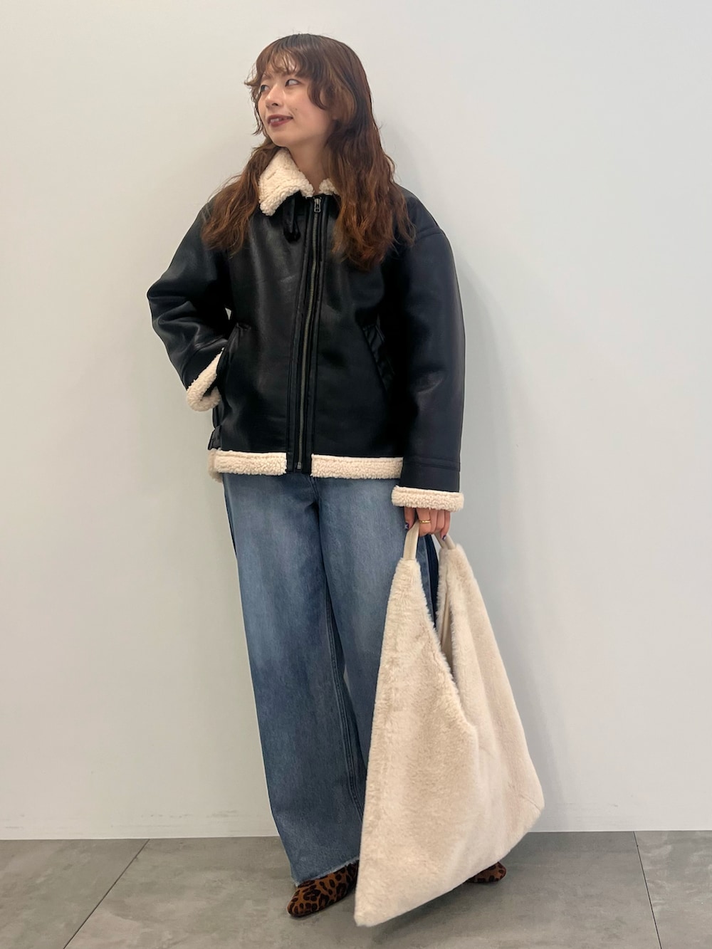 ブルー系のデニムパンツ、ブラック系のその他アウター、ベージュ系のショルダーバッグを着用したレディースの秋コーディネートの2枚目の写真