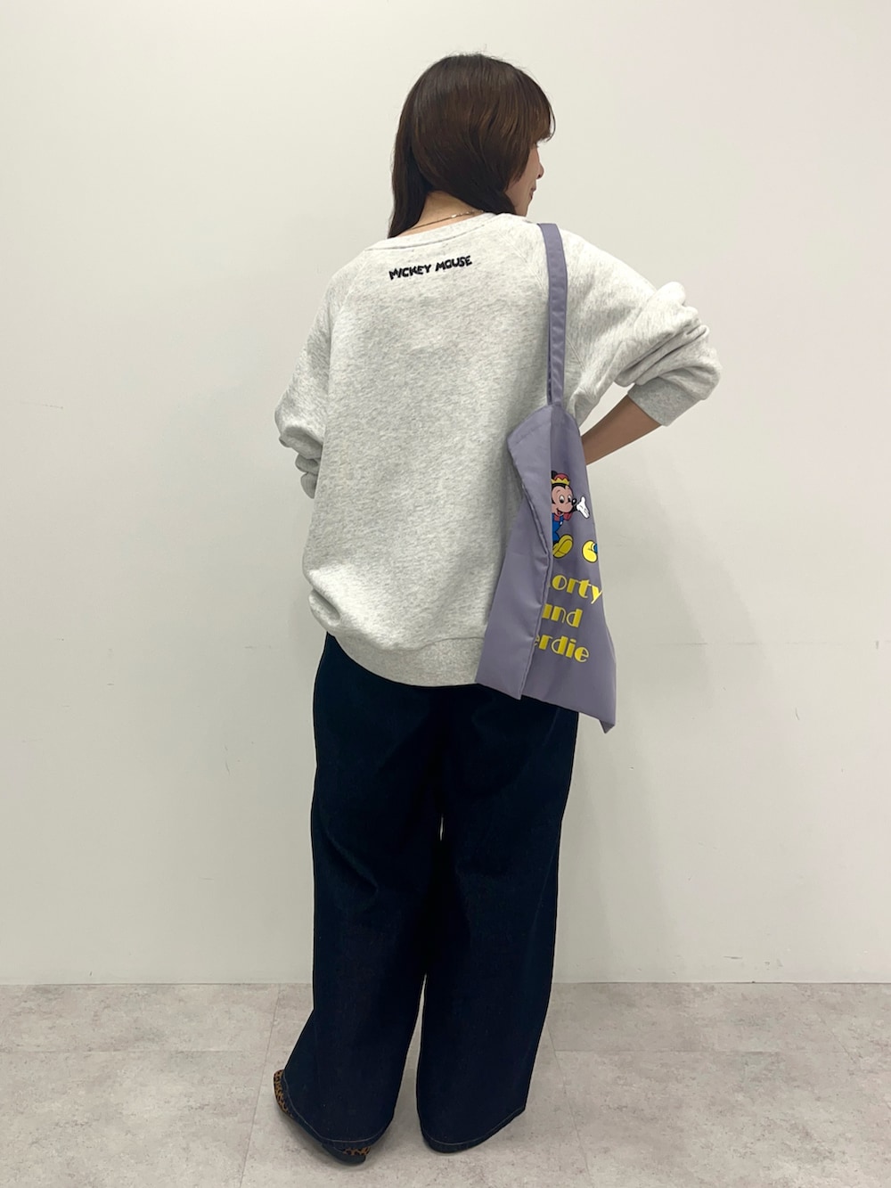 グレー系のスウェット、ブルー系のデニムパンツ、パープル系のトートバッグを着用したレディースの冬コーディネートの3枚目の写真