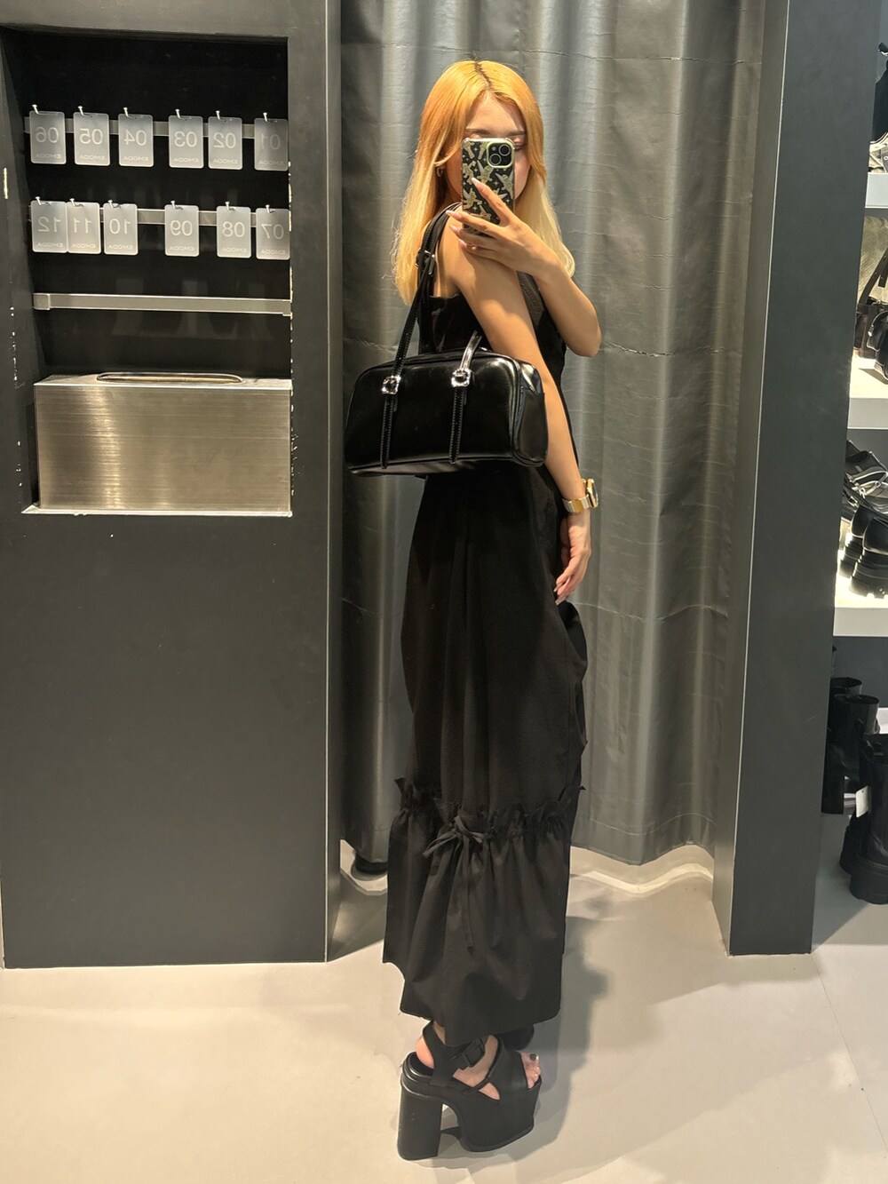 ブラック系のハンドバッグ、ブラック系のサンダル、ブラック系のワンピースを着用したレディースの春コーディネートの2枚目の写真