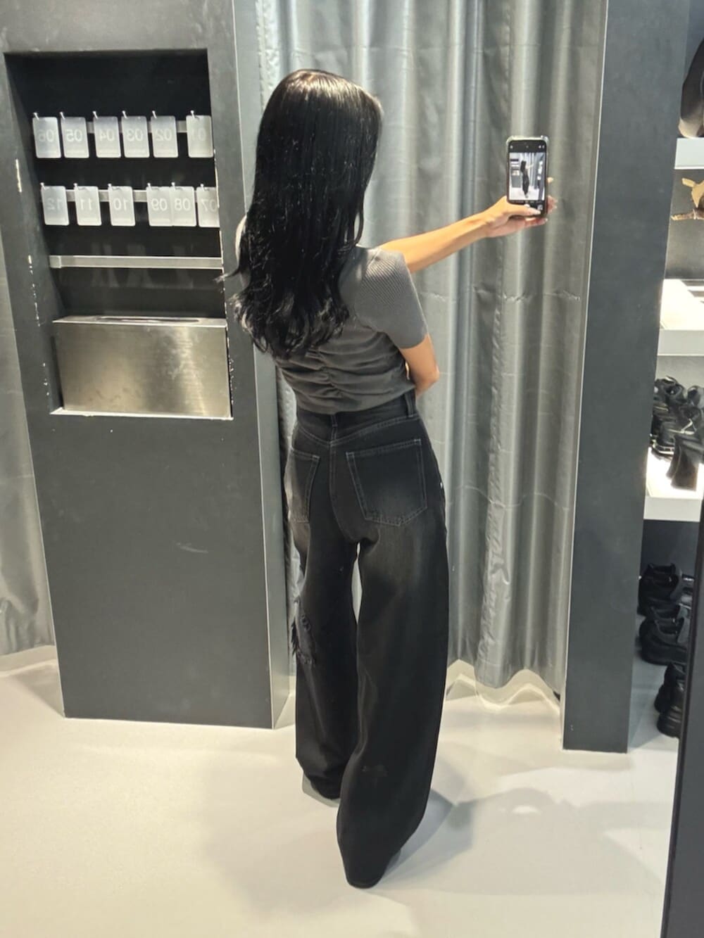 グレー系のニット/セーター、ブラック系のデニムパンツ、ブラック系のブーツを着用したレディースの秋コーディネートの3枚目の写真