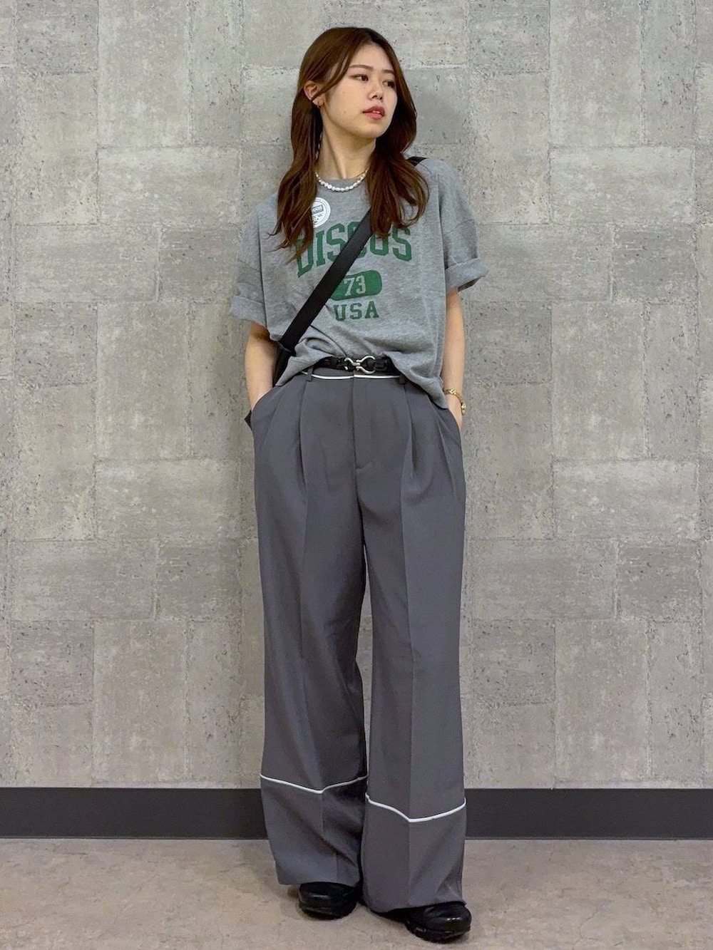 グレー系のTシャツ/カットソー、ブラック系のショルダーバッグ、グレー系のスラックスを着用したレディースの春コーディネートの2枚目の写真