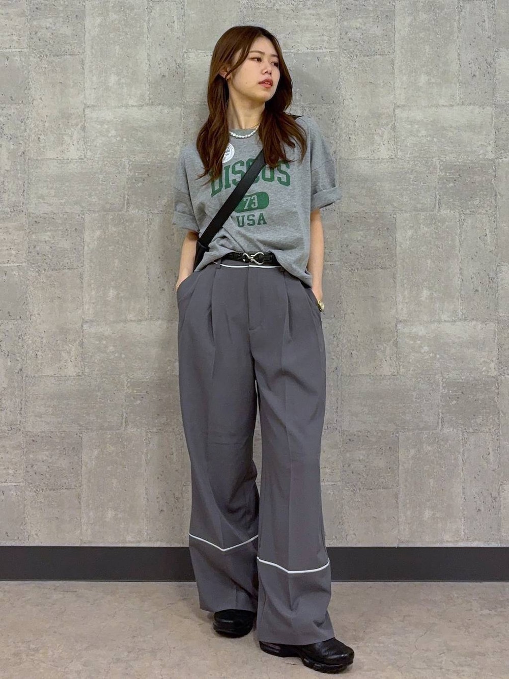 グレー系のTシャツ/カットソー、ブラック系のショルダーバッグ、グレー系のスラックスを着用したレディースの春コーディネートの3枚目の写真